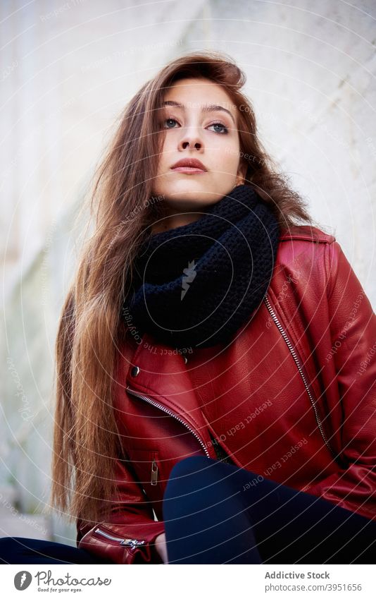 Confident young female millennial sitting on the street woman chill self assured building city relax alone confident trendy cool charismatic leather jacket