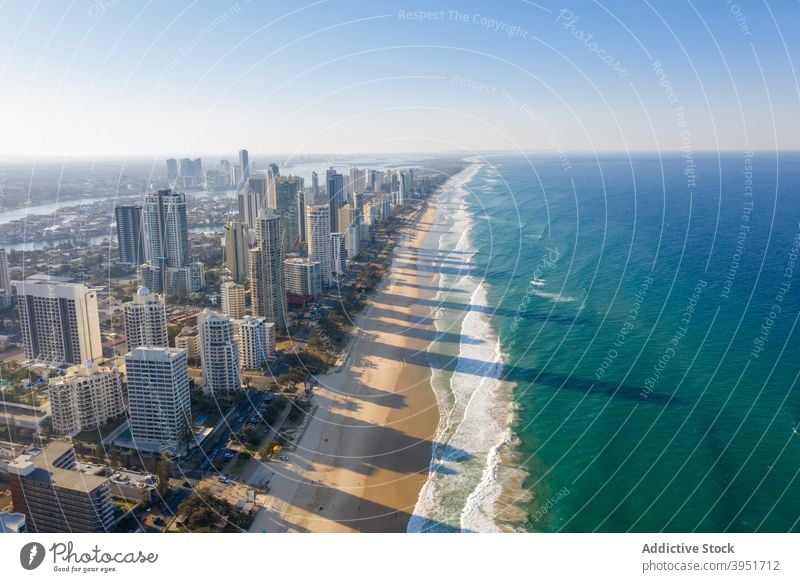 Turquoise sea with sandy beach in contemporary coastal city with modern architecture ocean cityscape travel seashore skyscraper coastline building