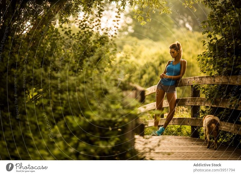 Sportswoman standing on wooden path in park sportswoman training break relax slim athlete summer female salburua vitoria gasteiz spain lean fence sportswear