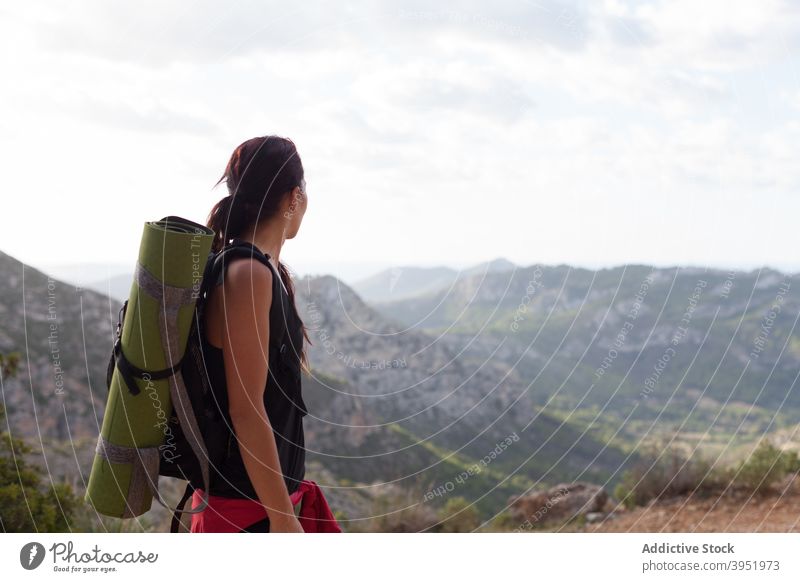 Anonymous woman admiring seascape from mountain top during trekking admire landscape hiker nature edge recreation enjoy relax female young activewear backpack