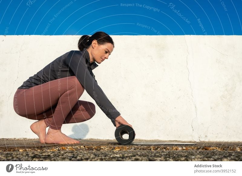 Slim woman with yoga mat on sunny day prepare ready practice slim calm harmony female sportswear zen tranquil barefoot slender wellness healthy activewear