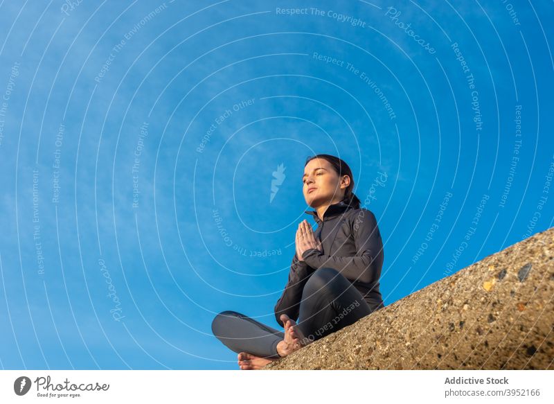 Carefree woman doing yoga in Lotus pose lotus pose meditate asana harmony peaceful relax padmasana female stone mudra sunny healthy zen eyes closed practice