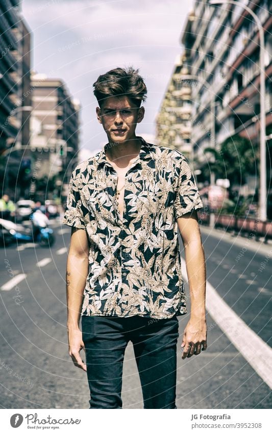 Young man with tough guy face walking in the middle of the street. portrait young skateboarder urban model fashion retro attitude look gaze poster frontal