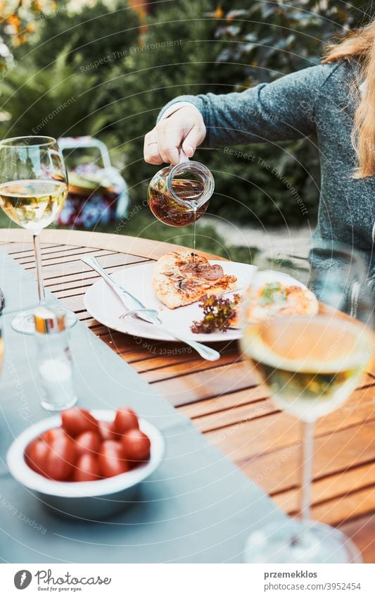 Family and friends having meal - pizza, salads, fruits and drinking white wine during summer picnic outdoor dinner in a home garden backyard beverage