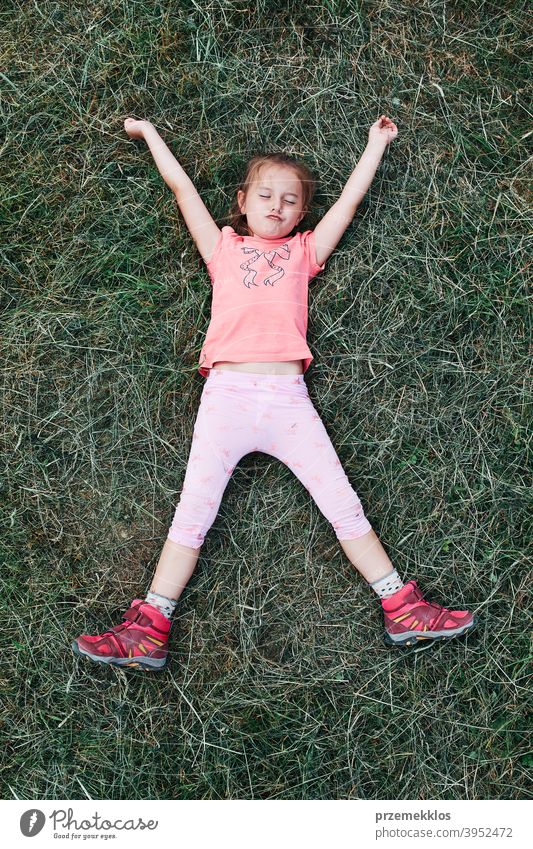 Little girl laying playing on grass enjoying summer day during vacation trip happy excitement enjoyment leisure emotion positive lying lifestyle activity