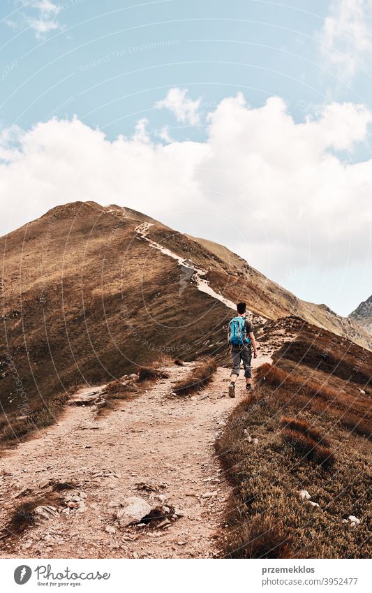 Young man with backpack hiking in a mountains, actively spending summer vacation activity adventure freedom healthy joy leisure nature park recreation spring