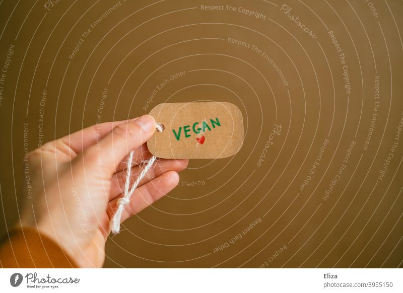 Hand holding a label with the word vegan written on it. Vegan lifestyle. vegan lifestyle vegan products Shopping Consumption Products Label commodities