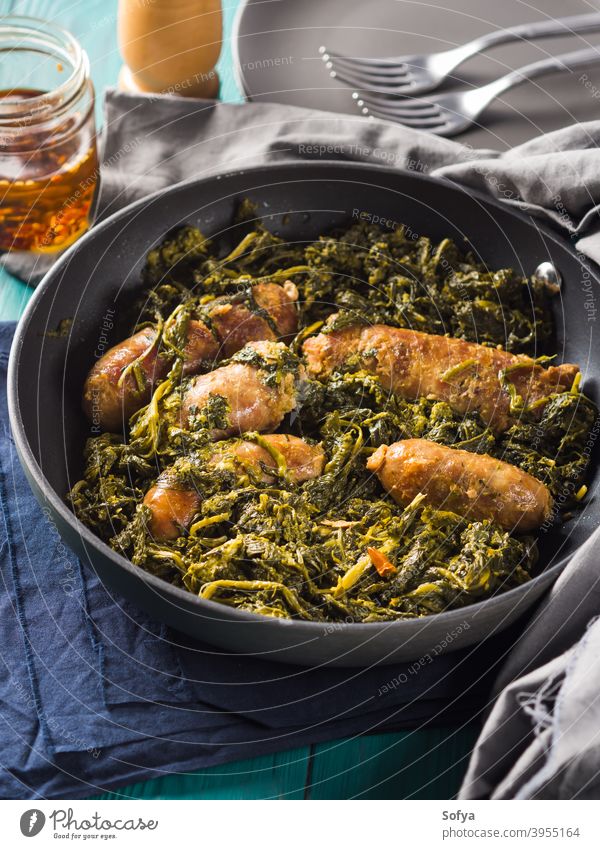 Italian sausages with rapini broccoli in a skillet meat italian kale black second dish dinner lunch meal serve table wooden set green traditional neapolitan