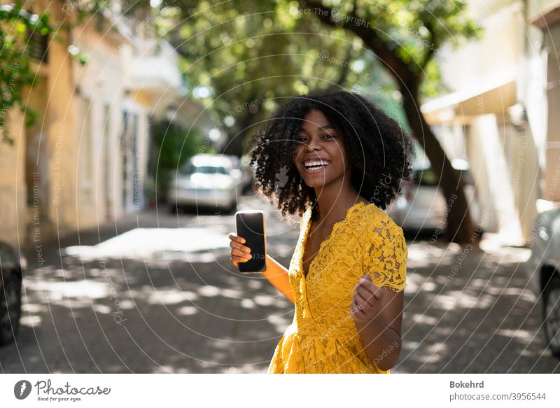 Young black woman with curly hair, in yellow dress and with styles, attitude, laughing, happy individuality ethnicity skin smiling hairstyle message afro