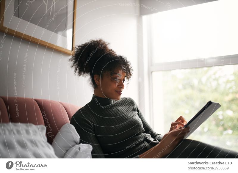 Woman relaxing on bed at home reading or streaming tv show on digital tablet woman tablet computer e-book watching film movie entertainment lockdown covid-19