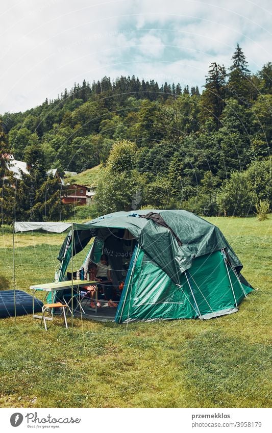 Tent with people inside standing on campsite. Family living in a tent spending summer vacation in mountains family tourism recreation natural life campground