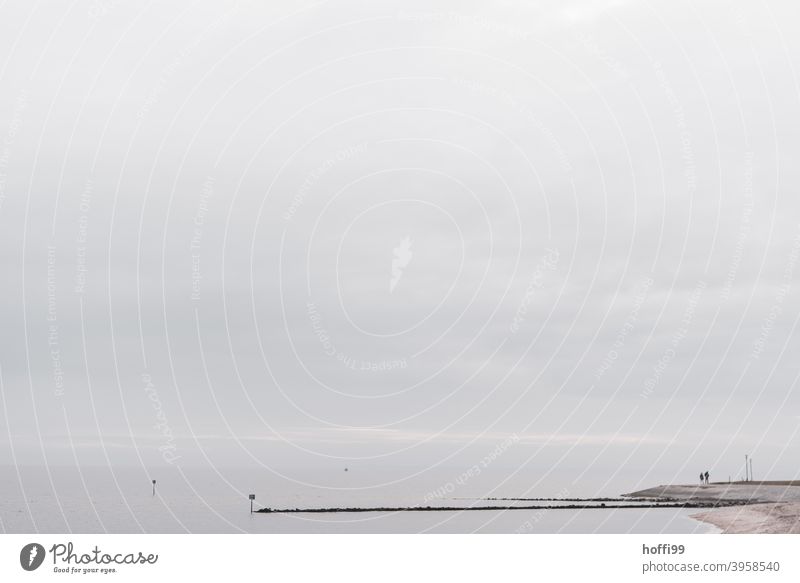 two people standing at a headland / groyne and looking at the sea - winter in the north North Sea coast Break water couple shallow water Winter Relaxation