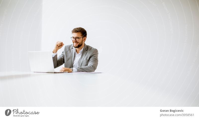 Young man working on laptop in bright office adult attractive beautiful behind business caucasian communication computer confident day desk elegant employee