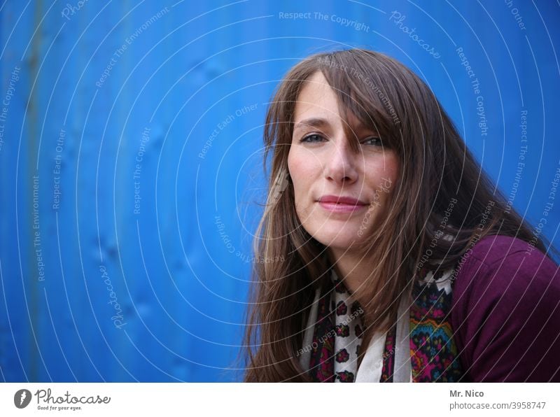 Portrait against blue background Feminine Face portrait Woman Looking Hair and hairstyles Upper body Smiling naturally Sympathy Contentment Emanation Moody