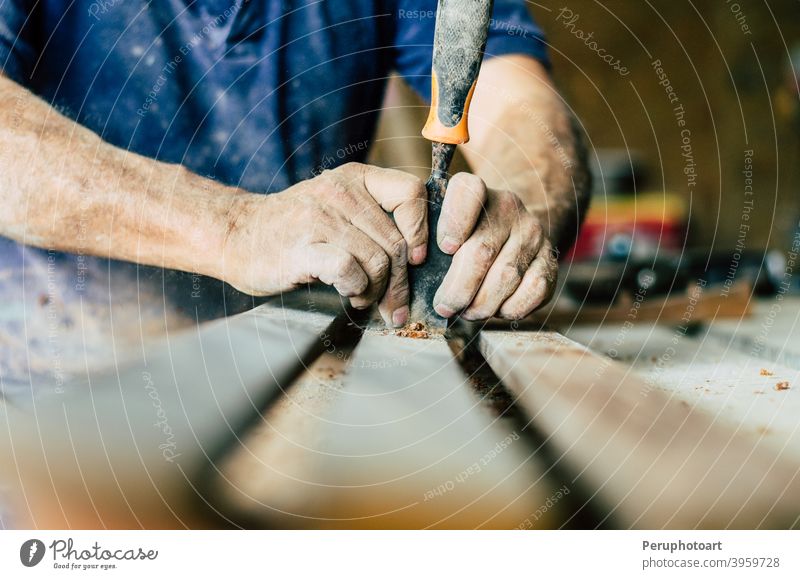 Professional carpenter at work, he is carving wood using a woodworking tool, hands close up, carpentry and craftsmanship concept workshop vintage carver chisel