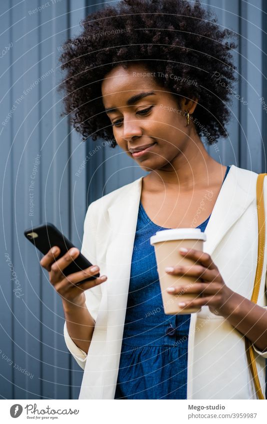 Business woman using her mobile phone outdoors. afro business black modern style brunette gadget positive concept connection application sms texting