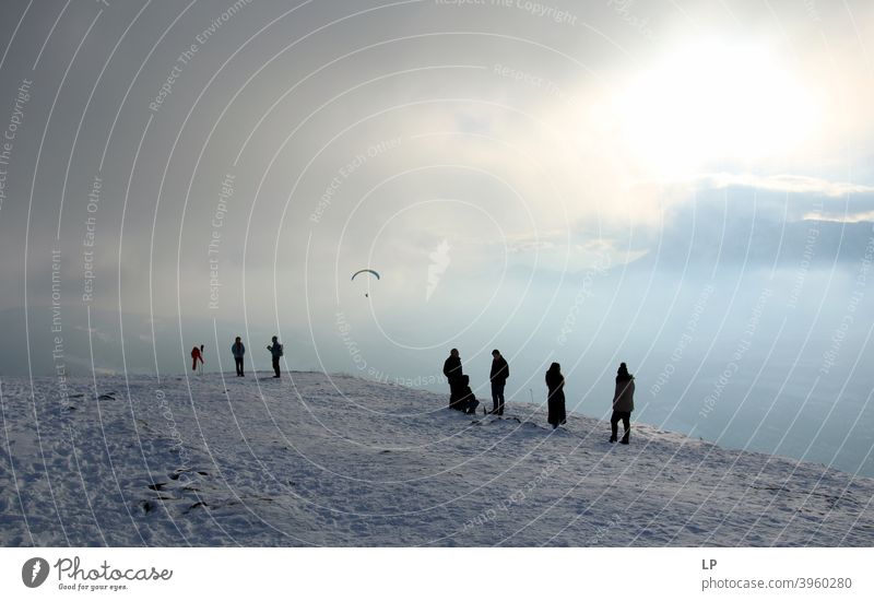 silhouettes waiting on the moutain on a foggy day watching a paraglider Faith & Religion praying Prayer background Forward Contentment Posture Vacation & Travel