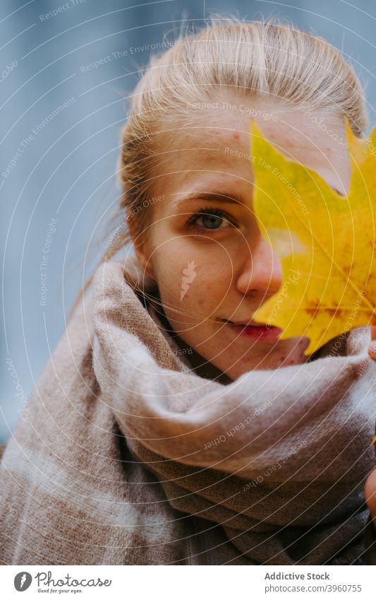 Smiling woman with maple leaf cover face smile tender autumn season fall foliage female yellow color scarf warm content happy glad charming nature bright