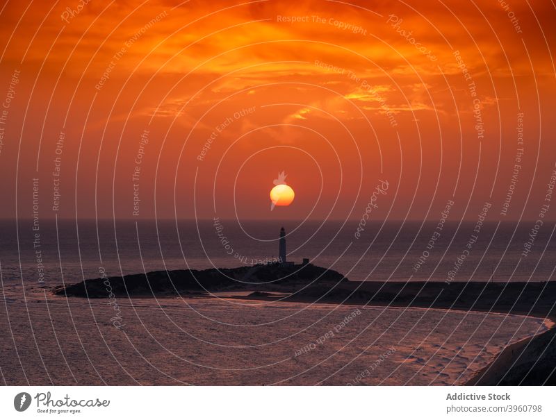 Lonely lighthouse on hill against sunset sun sea orange beacon seascape sky sundown cadiz andalucia spain magnificent coast shore picturesque breathtaking tower