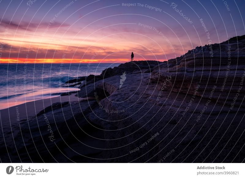 Anonymous traveler enjoying sunset over sea admire breathtaking silhouette vibrant sundown rock beach cadiz andalucia spain shore tourist scenery picturesque