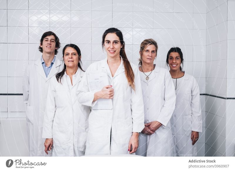 A group doctors in white coats stand while one of them hold a report CrotoChic analysis analyzing assertive checking clinic confident consultant diagnosis