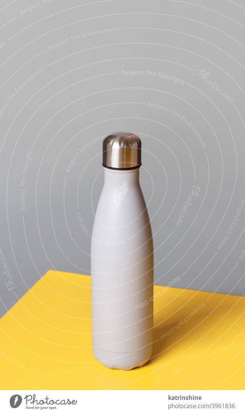 Grey reusable steel bottle on grey and yellow background monochrome mockup insulated ecologic water thermo aluminum blank close up concept copy space