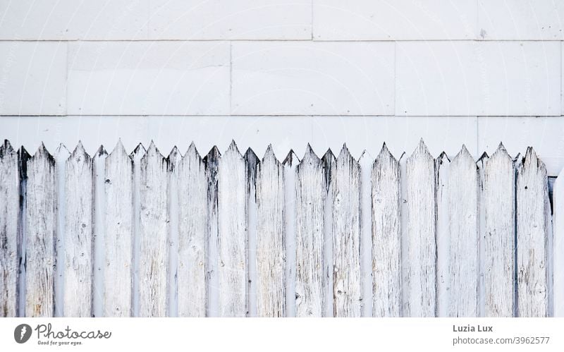 Facade and forms, an old wooden fence with sharp jags in front of facade panels, which have also been affected by the ravages of time. Fence Fence posts