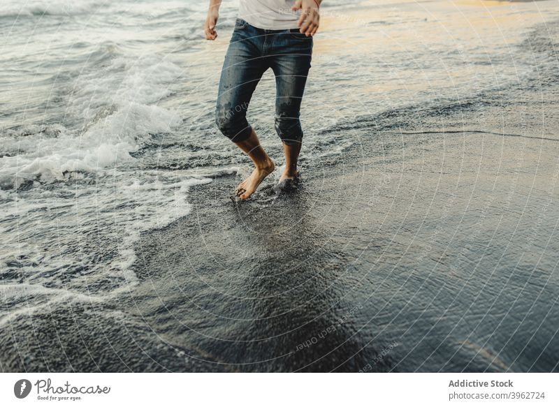 Man walking along wet sandy seashore man beach wave barefoot traveler coast ocean male sunset vacation lifestyle nature water relax tourism summer leg evening