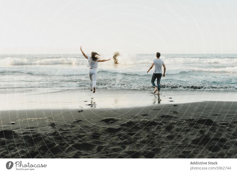 Happy couple running towards waving sea wave romantic together carefree beach love happy coast freedom fresh young tenerife island canary spain tourism