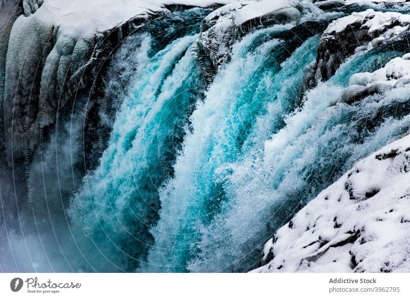 Amazing waterfall in mountainous terrain in winter flow stream rapid snow rocky landscape iceland nature scenery picturesque environment cold energy magnificent