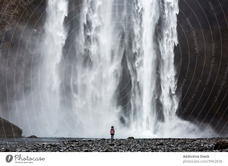 Explorer standing near waterfall on sunny day traveler mountain vacation landscape amazing flow stream tourism iceland explore explorer nature wanderlust