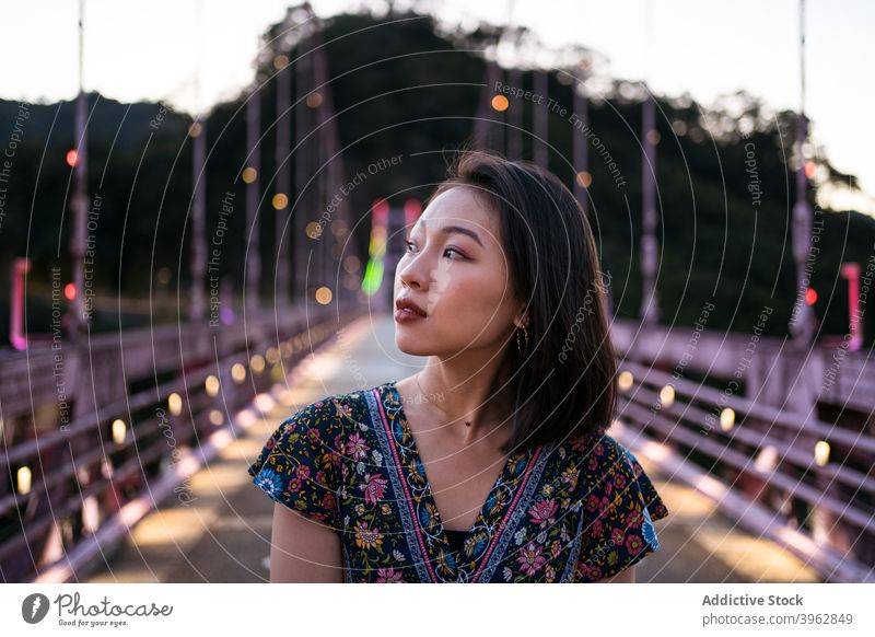 Carefree ethnic woman on bridge in evening summer vacation suspension carefree enjoy twilight footbridge female asian taiwan delight happy relax dusk smile