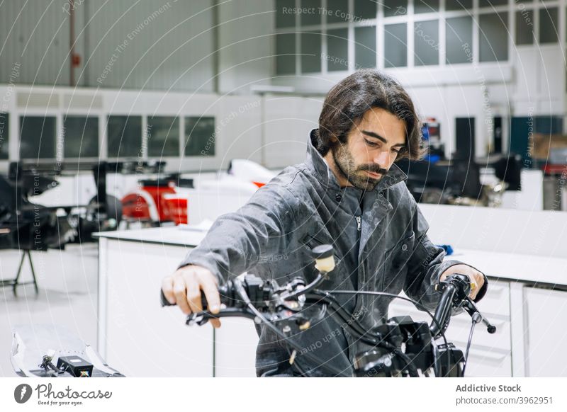 Busy technician in motorcycle workshop mechanic custom man examine workwear check handlebar motorbike male repairman service modern bright occupation garage job