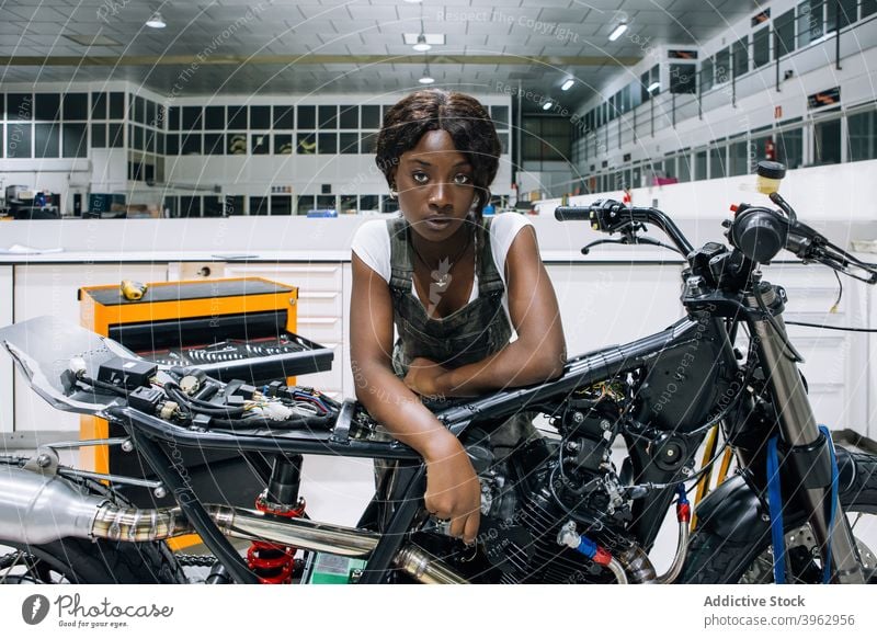 Black woman with motorcycle working in workshop mechanic motorbike custom professional vehicle repair assemble female african american black ethnic job