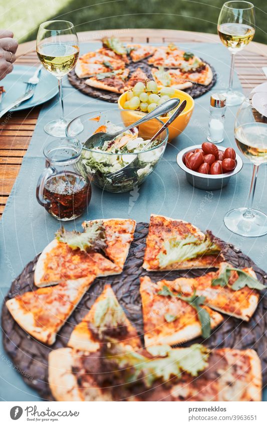 Dinner in a home garden. Pizza, salads, fruits and white wine on table in a backyard beverage celebration dinner dish drink eating feast food gathering having