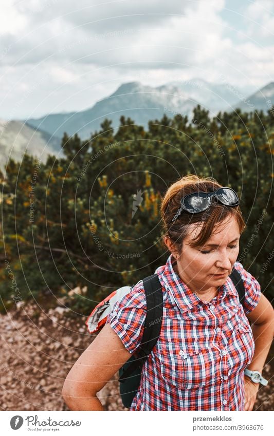 Woman with backpack hiking in a mountains, actively spending summer vacation, having break after going up on a hill activity adventure female freedom green