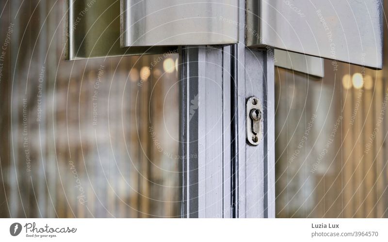 Entrance door of an old factory, imposing door handles only partly visible, behind it warm light Portal Front door Door handles Door lock Warm light