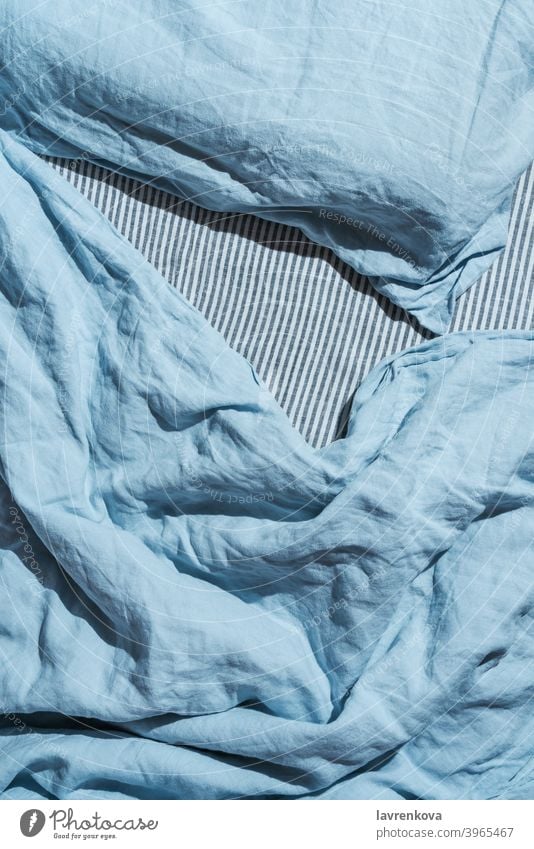 Flatlay of blue linen bed cloths and pillow sleep sheets bedroom blanket textile relaxation style clean comfortable fabric morning texture top view cotton home