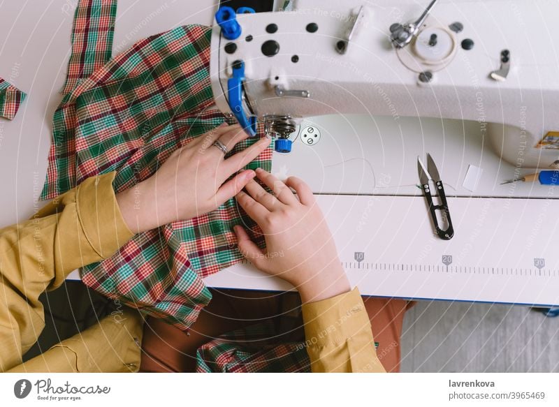 Top view of woman working with sewing machine in her workshop fabric tailor material seamstress clothing needle craft thread textile business worker dress