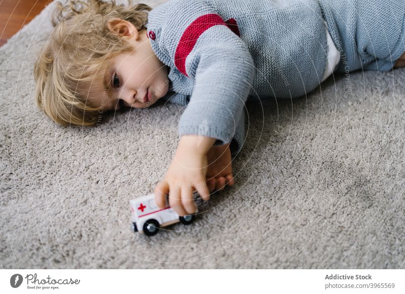 Serious kid playing with toy at home boy child game car activity cute little lying childhood lifestyle preschool free time childcare enjoy recreation