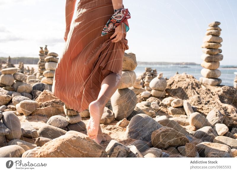 Trendy young lady resting on sandy coast amidst stones in daytime woman relax beach style vacation holiday nature traveler feminine recreation female trendy