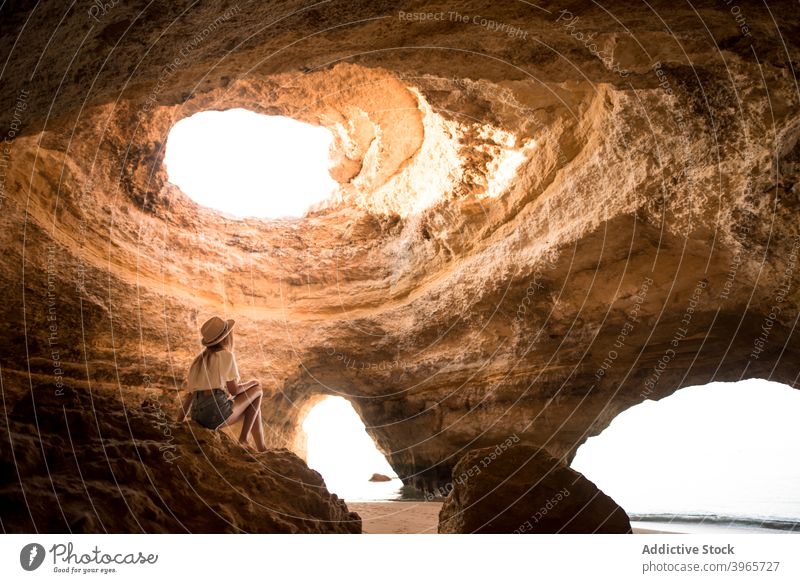 Unrecognizable woman admiring cave near sea admire vacation ceiling hole sunny daytime travel algarve portugal female hat casual ocean idyllic rock stone