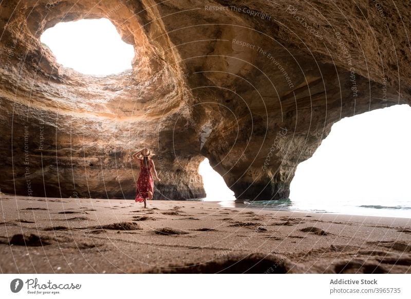 Anonymous woman walking in cave near sea summer sunny sand stone travel algarve portugal rock shore coast ocean vacation tourism water nature wanderlust