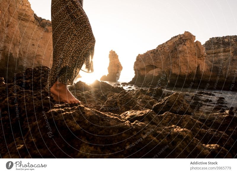 Unrecognizable woman admiring rocky landscape near sea admire vacation sunny daytime travel algarve portugal female barefoot casual ocean idyllic stone tourism