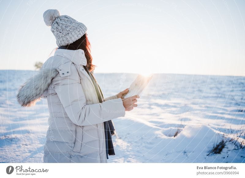 beautiful young woman at sunset in snowy mountain reading a map. Travel, Nature and technology concept. winter season hiking cold covered caucasian forest