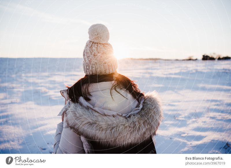 back view of woman in snowy mountain wearing modern coat at sunset. winter season. nature hiking cold caucasian forest wanderlust travel walk hiker tour tourism