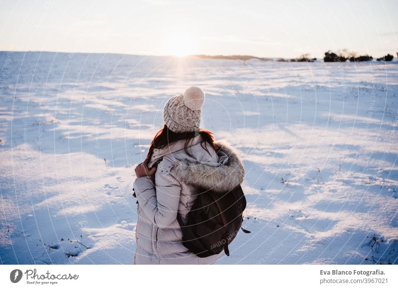 back view of woman in snowy mountain wearing modern coat at sunset. winter season. nature hiking cold caucasian forest wanderlust travel walk hiker tour tourism