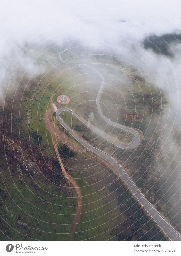 Modern round helipad in green suburbs road curve mountain landscape highland picturesque terrain nature scenery scenic hill valley idyllic destination