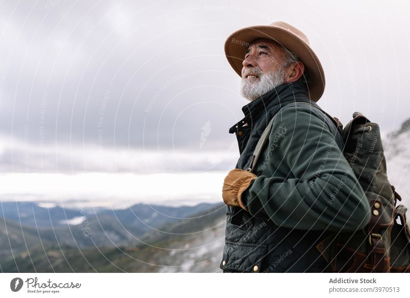 Senior traveler in mountains in winter man senior explore admire highland backpack scenic caceres spain extremadura wanderlust male elderly nature snow