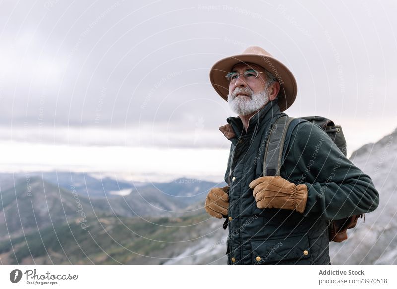 Senior traveler in mountains in winter man senior explore admire highland backpack scenic caceres spain extremadura wanderlust male elderly nature snow